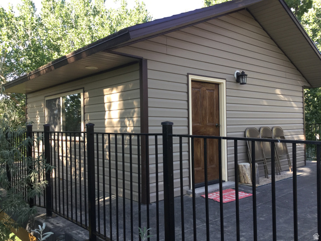 1040 West Mill Road Ferron, UT 84523 - Photo 104 of 117 Exterior building featuring horizontal siding and a wood-finish entry door, complemented by an outdoor light fixture