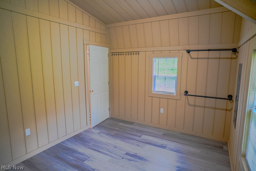 1547 Providence Road Elizabeth, WV 26143 - Photo 15 of 32 Interior room featuring wood-finish flooring, vertical plank wall paneling, a single window with blinds, and two wall-mounted industrial-style racks