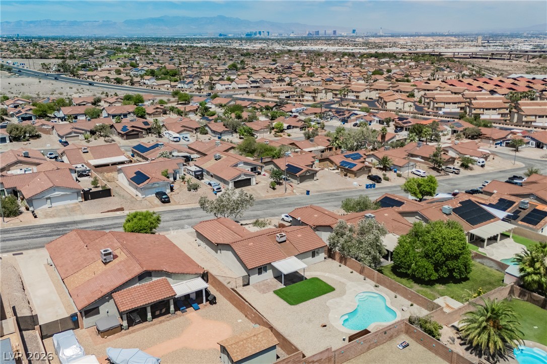 112 Iridescent Street Henderson, NV 89012 - Photo 20 of 24 An aerial perspective reveals a vibrant neighborhood with individual backyard pools, set against a distant cityscape.