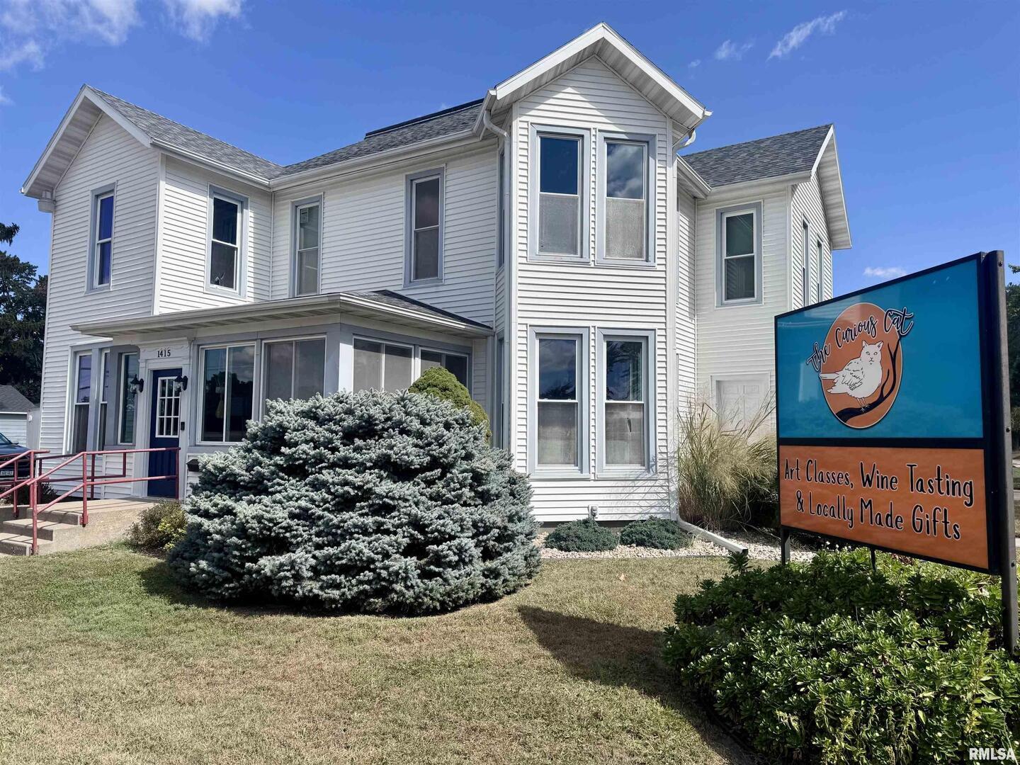 1415 4th Street Fulton, IL 61252 - Photo 2 of 58 a view of a white house with large windows and a flower garden