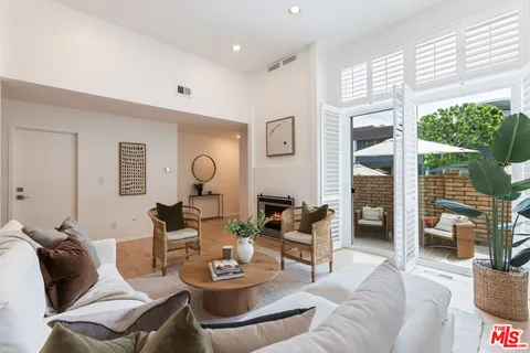a living room with furniture a rug potted plant and a large window