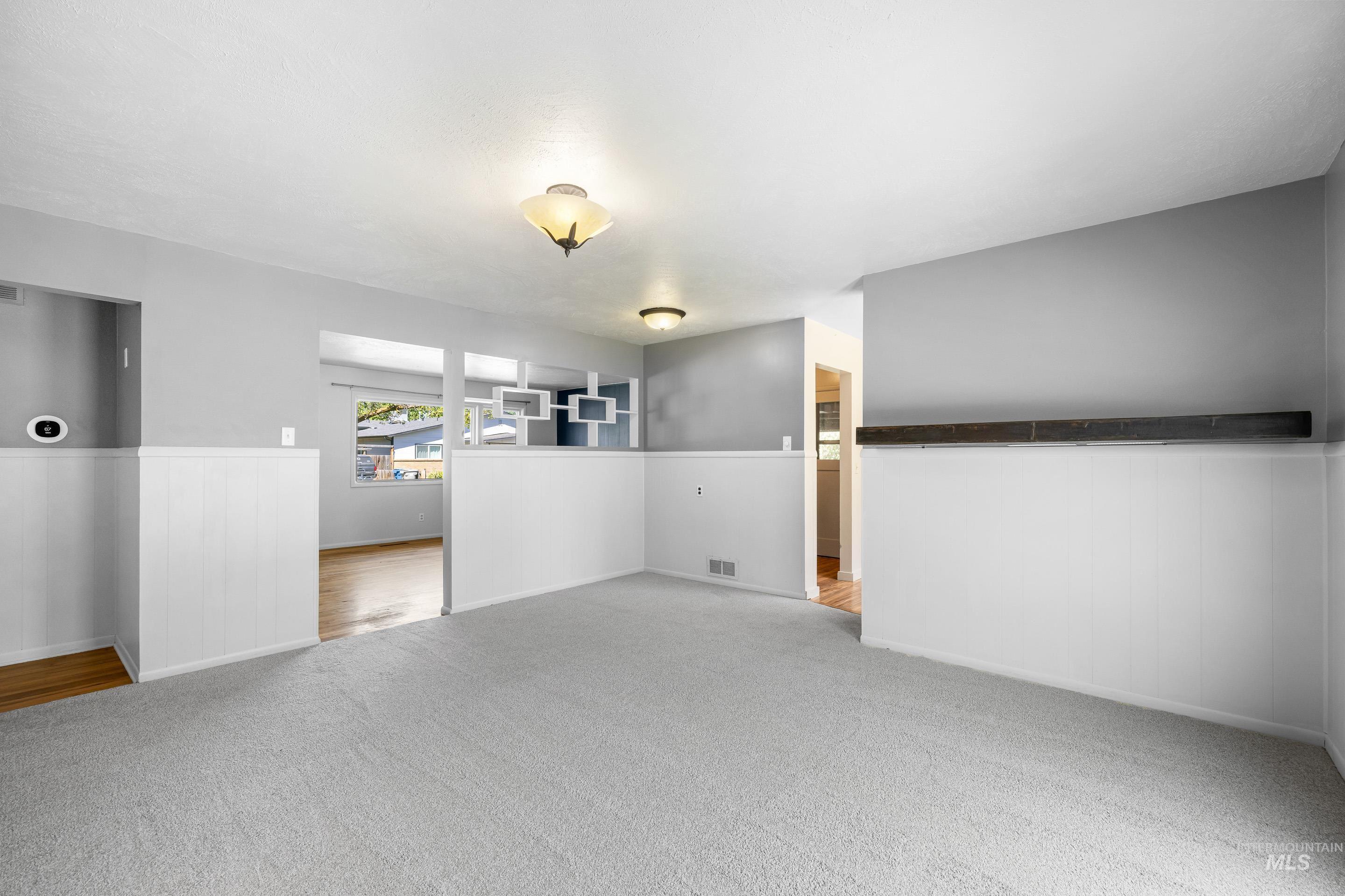 708 South Phillippi Street Boise, ID 83705 - Photo 6 of 25 Spacious interior featuring light gray carpeting, white wainscoting, and a decorative wood shelf