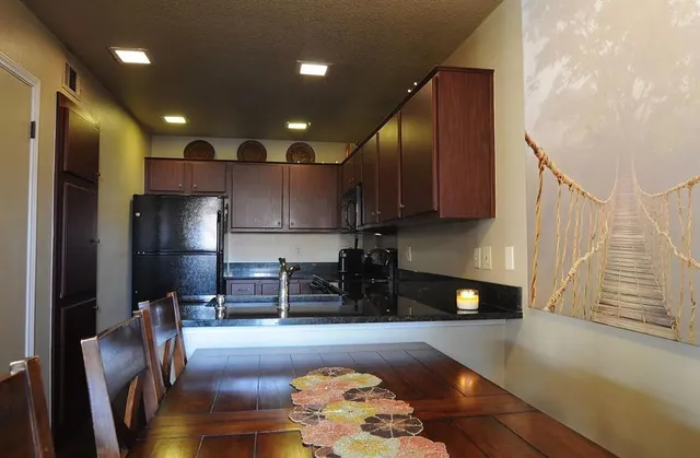 a kitchen with stainless steel appliances granite countertop a refrigerator a stove and a wooden cabinets