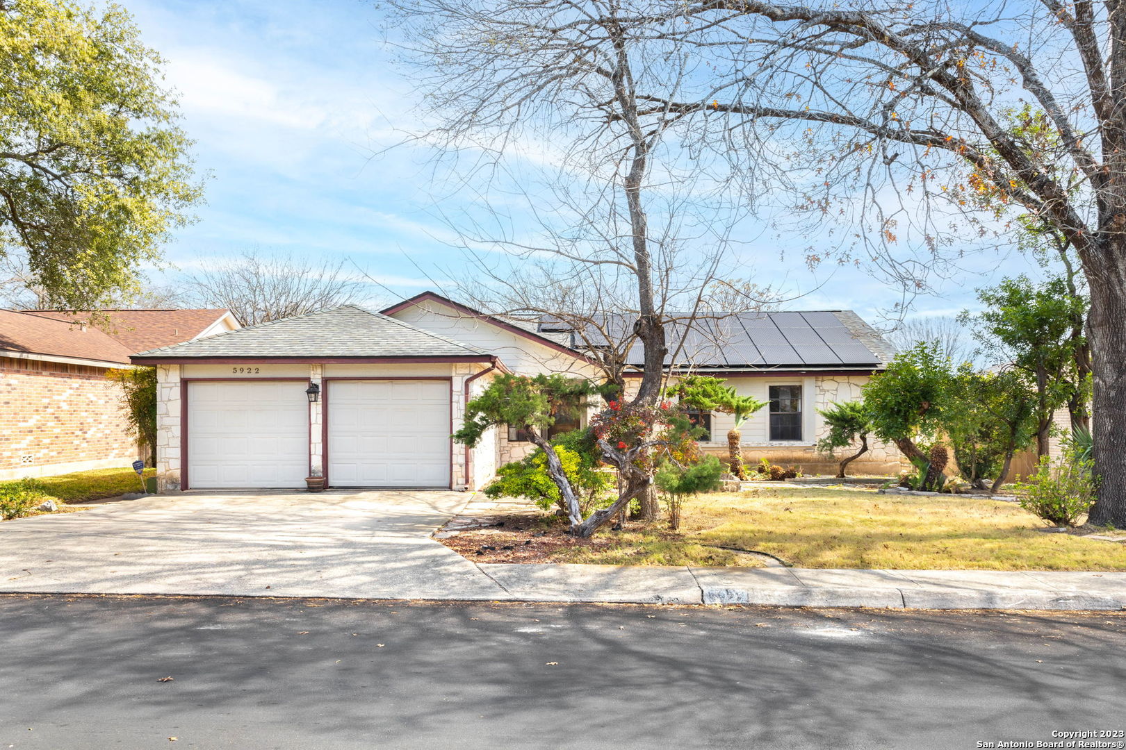 a view of a house with a yard and a large tree