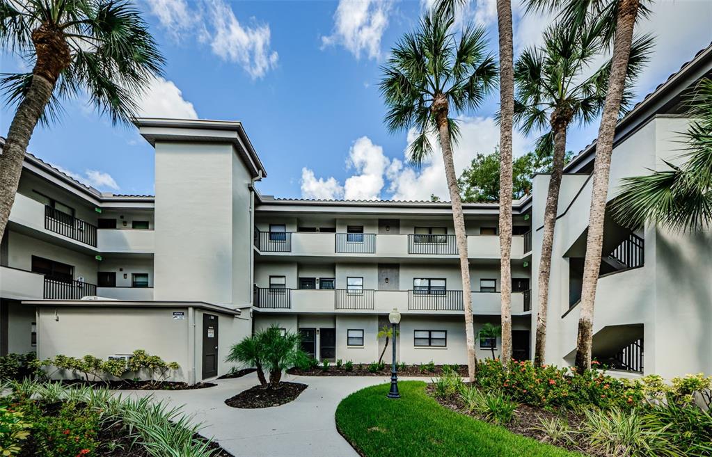 2650 Countryside Boulevard, Unit F110 Clearwater, FL 33761 - Photo 2 of 26 a front view of a residential apartment building with a yard and potted plants