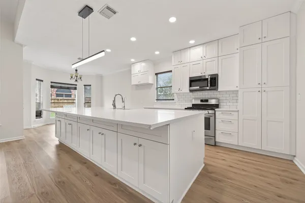a kitchen with kitchen island granite countertop a sink appliances cabinets and wooden floor