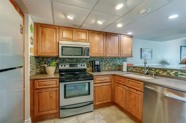 a kitchen with stainless steel appliances granite countertop a refrigerator a stove a sink and a microwave