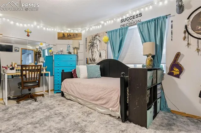 a bedroom with a bed a standing fan and a window