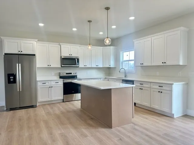 a kitchen with granite countertop white cabinets and stainless steel appliances