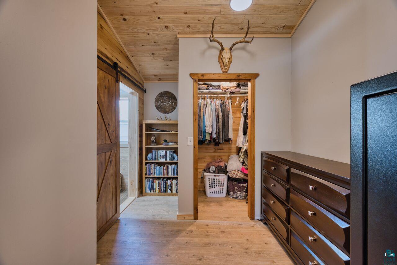 6925 Red Pine Road Virginia, MN 55792 - Photo 7 of 46 Spacious closet featuring light wood finished floors, a barn door, and vaulted ceiling