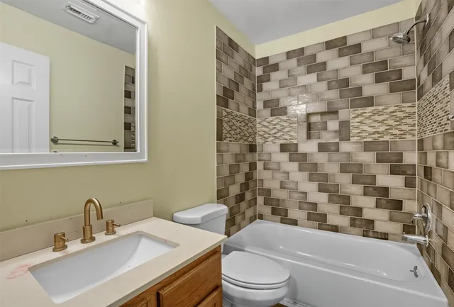 a bathroom with a bathtub shower sink vanity mirror and toilet