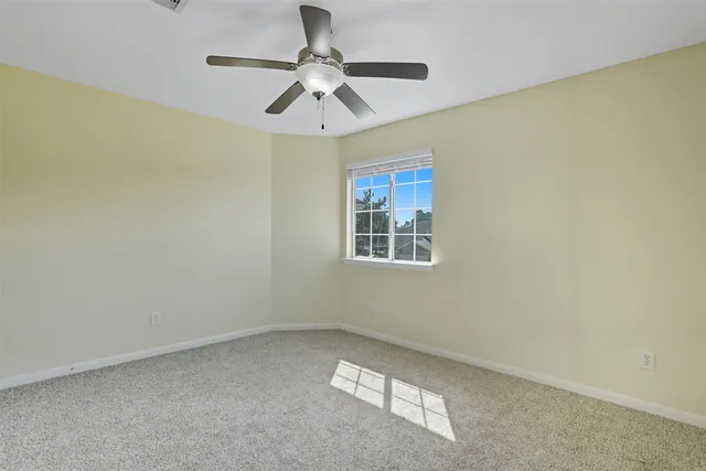 an empty room with a ceiling fan and a window