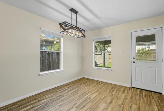 a view of an empty room with wooden floor and a window