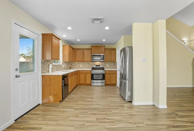 a large kitchen with a center island wooden floor stainless steel appliances and cabinets