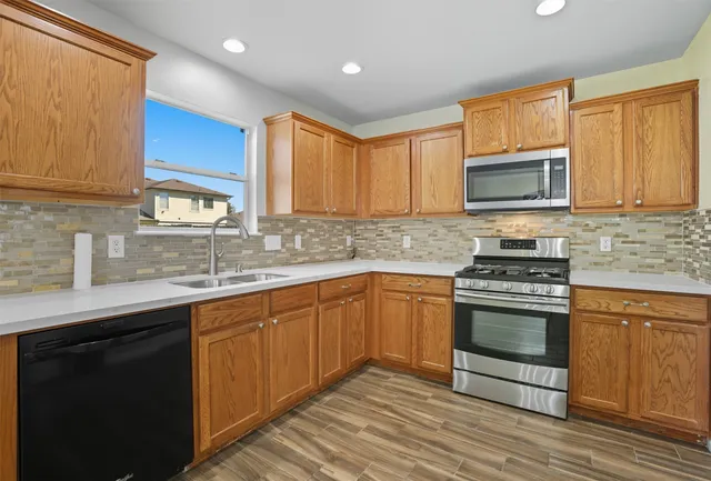 a kitchen with stainless steel appliances granite countertop wooden cabinets stove top oven and sink