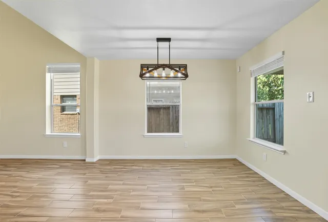 a view of an empty room with a window and wooden floor