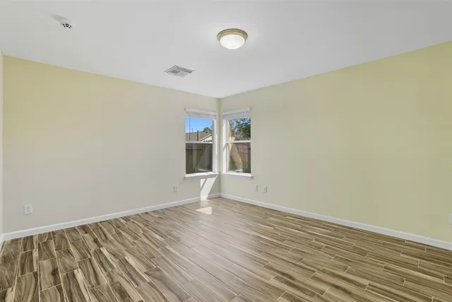 a view of an empty room with wooden floor and a window