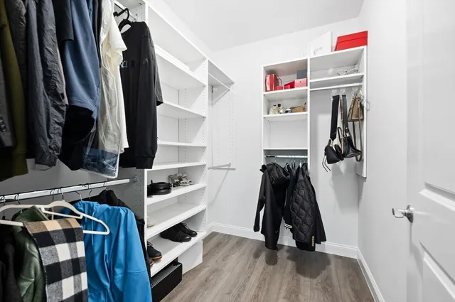 a walk in closet with wooden floor