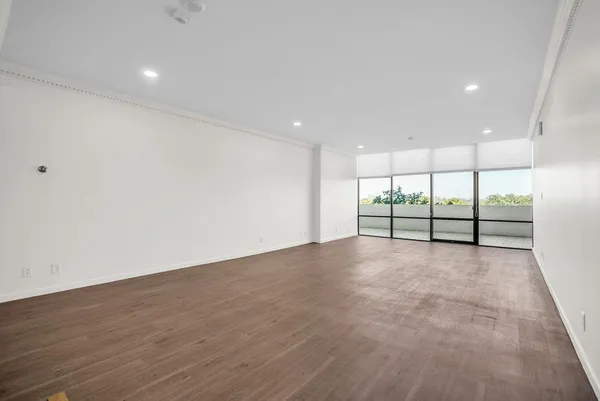 a view of an empty room with wooden floor and glass door