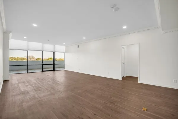 a view of an empty room with wooden floor and sliding window