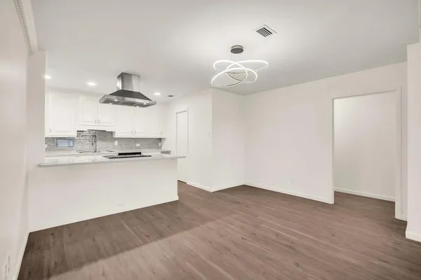 a large kitchen with a large window wooden floor and stainless steel appliances