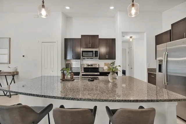 a kitchen with stainless steel appliances granite countertop a sink refrigerator and microwave