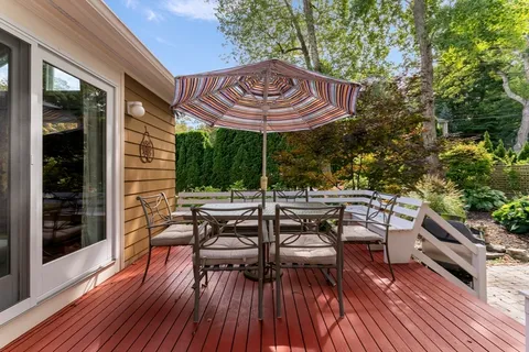 a view of a patio with table and chairs potted plants with wooden floor and fence