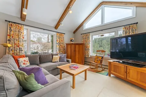 a living room with furniture a flat screen tv and floor to ceiling window