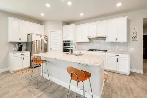 a kitchen with stainless steel appliances white cabinets and wooden floors