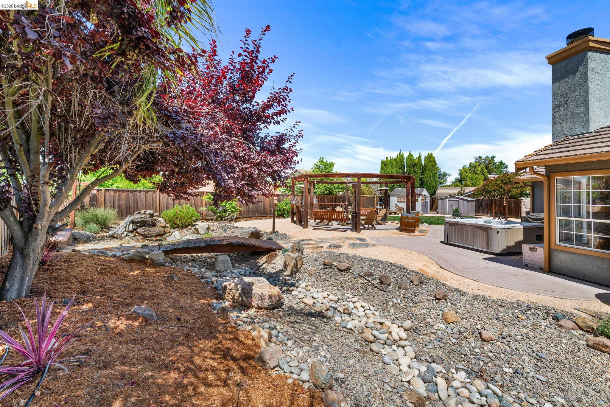 1186 El Rio Court Livermore, CA 94551 - Photo 40 of 60 Expansive backyard featuring a stone-lined dry creek bed, a decorative wooden bridge, an outdoor pergola, a concrete patio, and mature landscaping