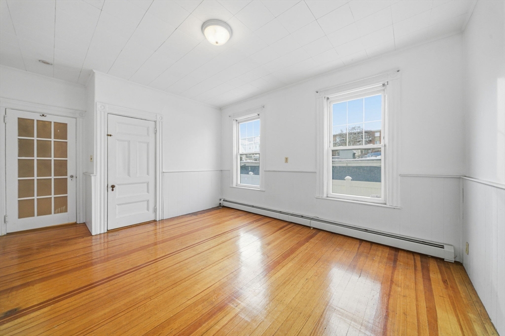 87 Burt Street Boston, MA 02124 - Photo 11 of 40 an empty room with wooden floor and windows