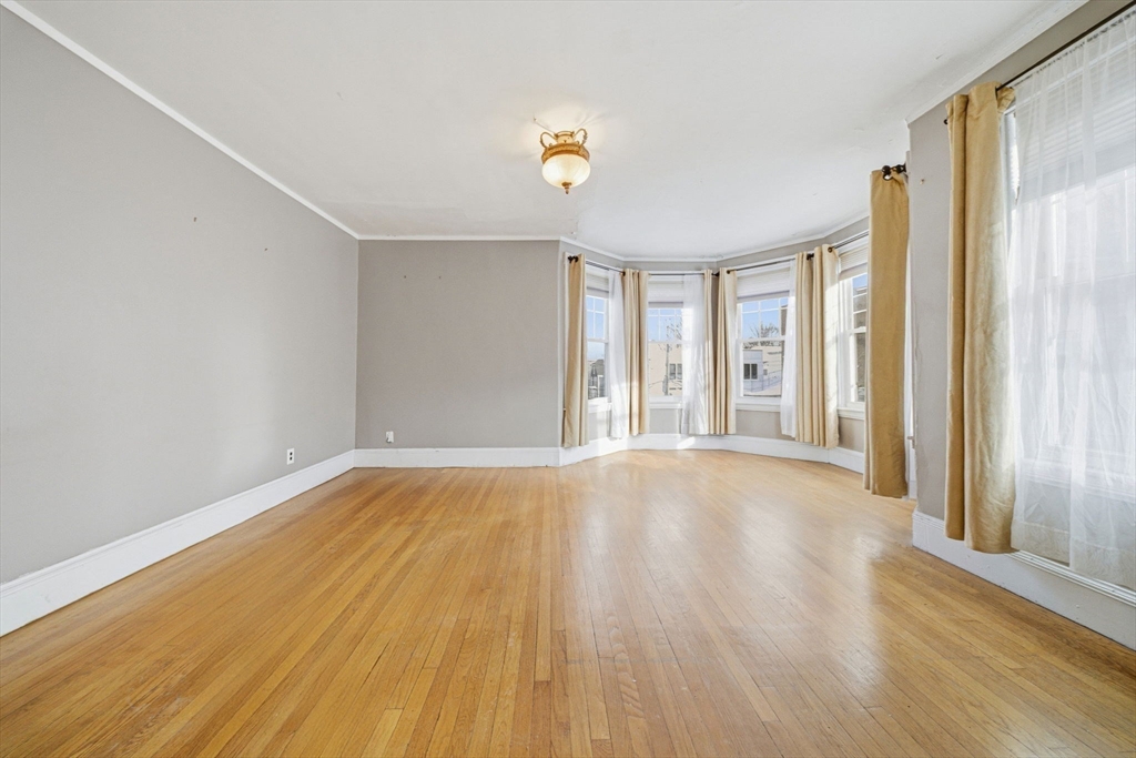 87 Burt Street Boston, MA 02124 - Photo 18 of 40 a view of an empty room with window and wooden floor