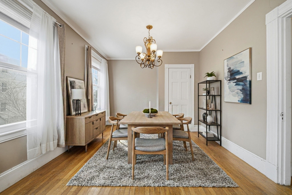 87 Burt Street Boston, MA 02124 - Photo 22 of 40 a dining room with wooden floor a chandelier a wooden table and chairs