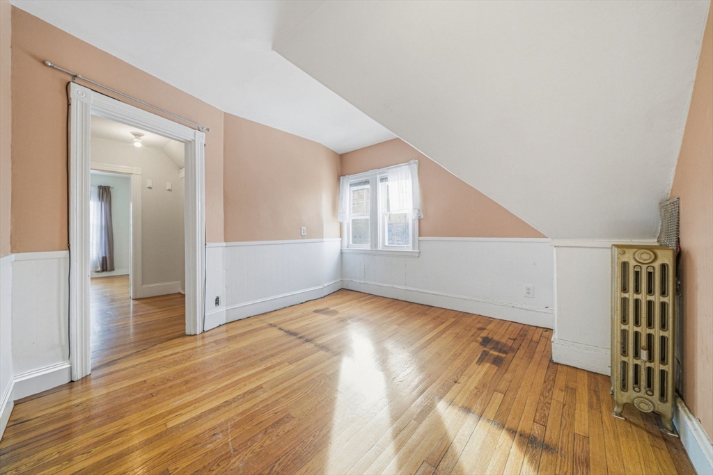 87 Burt Street Boston, MA 02124 - Photo 33 of 40 a view of an empty room with wooden floor and a kitchen