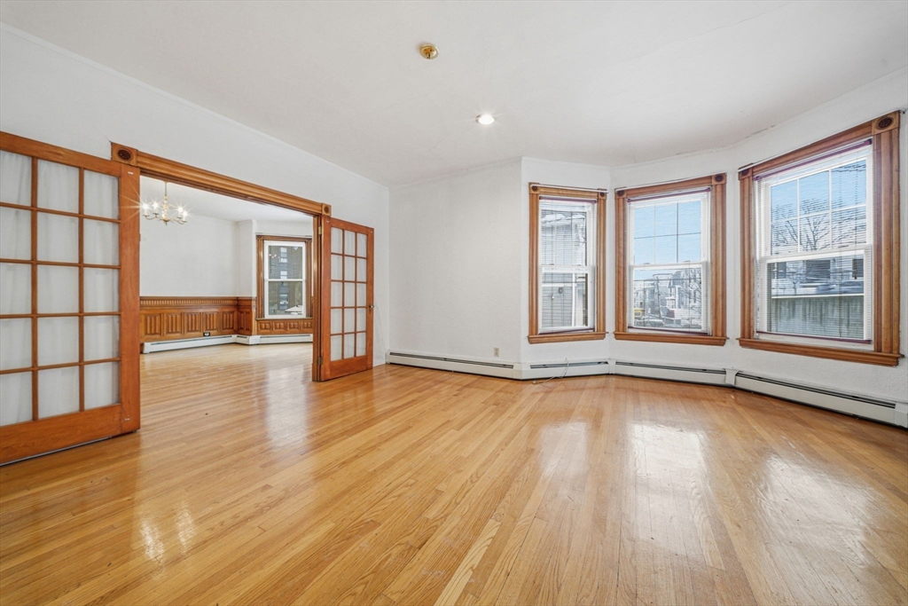 87 Burt Street Boston, MA 02124 - Photo 6 of 40 a view of an empty room with wooden floor and a window