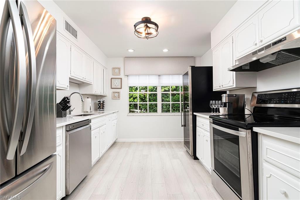 2728 Crayton Road Naples, FL 34103 - Photo 5 of 14 a kitchen with stainless steel appliances a refrigerator sink and stove top oven