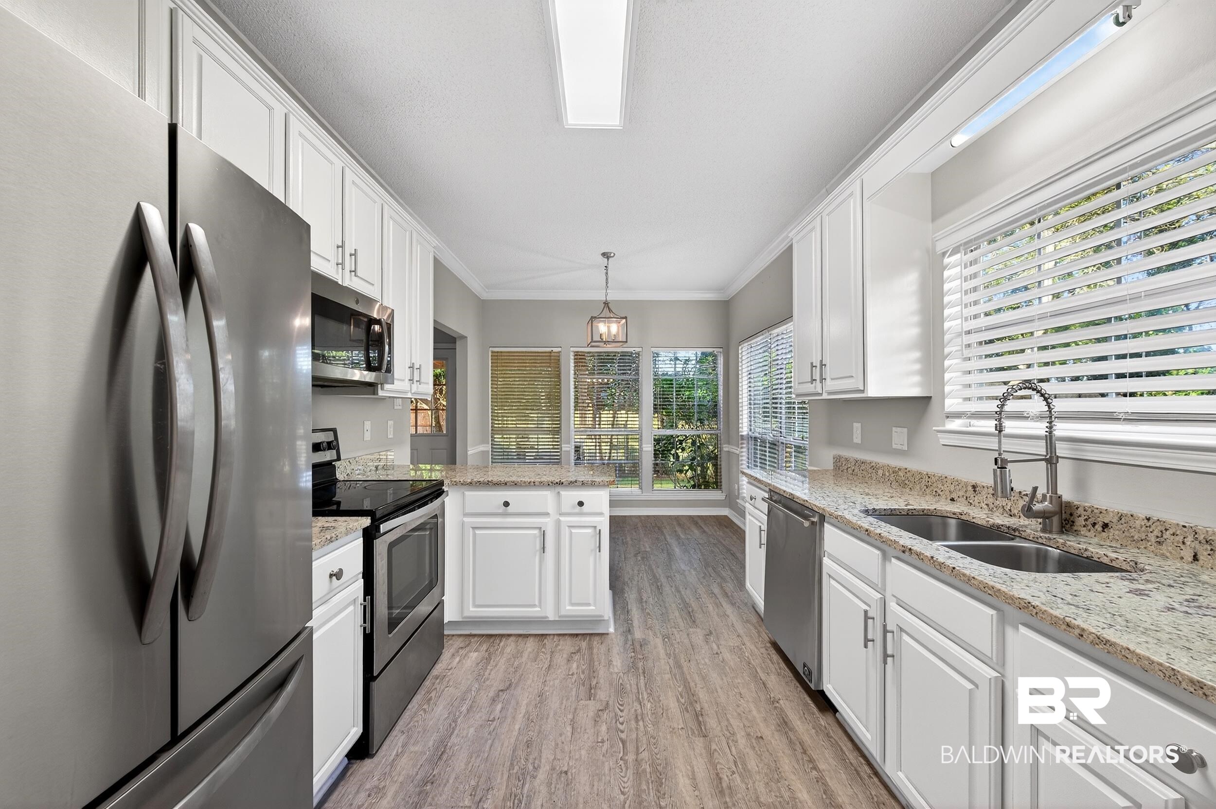 7050 Highpointe Place West Daphne, AL 36527 - Photo 15 of 66 Kitchen featuring stainless steel appliances, light stone countertops, white cabinetry, light wood finished floors, and ornamental molding