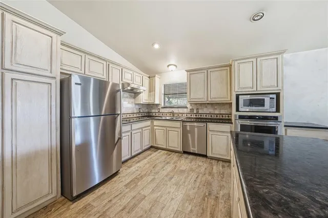 a kitchen with white cabinets stainless steel appliances and a refrigerator
