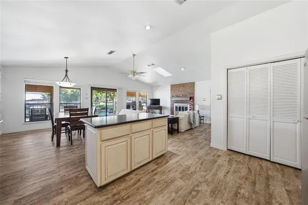 a kitchen with stainless steel appliances granite countertop a refrigerator a sink dishwasher a stove and a dining table with wooden floor