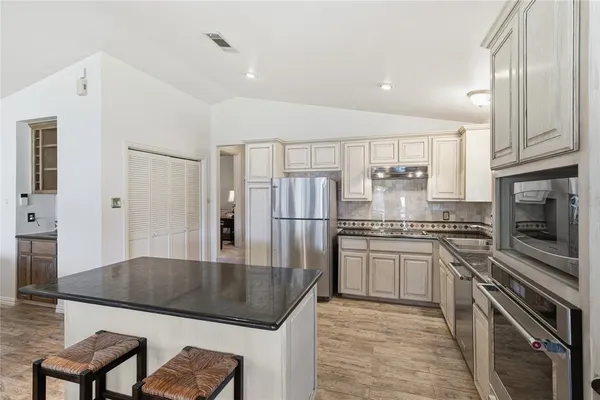 a kitchen with stainless steel appliances granite countertop a stove refrigerator sink and cabinets