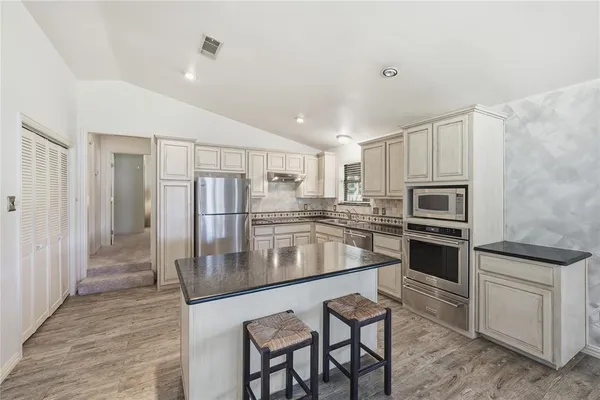 a kitchen with stainless steel appliances granite countertop a stove refrigerator sink and microwave