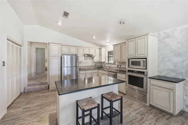 a kitchen with stainless steel appliances granite countertop a stove refrigerator sink and microwave