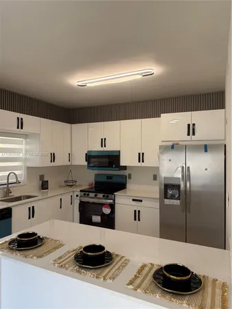 a kitchen with stainless steel appliances a stove a sink a refrigerator and cabinets