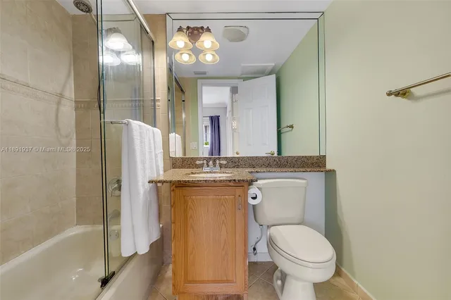 a bathroom with a granite countertop toilet a sink and a mirror