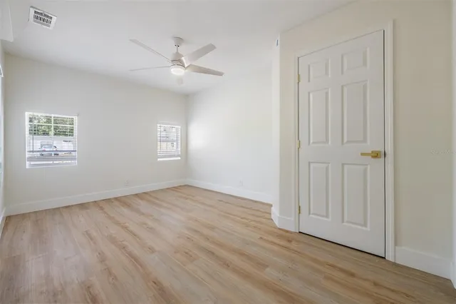 an empty room with wooden floor and windows