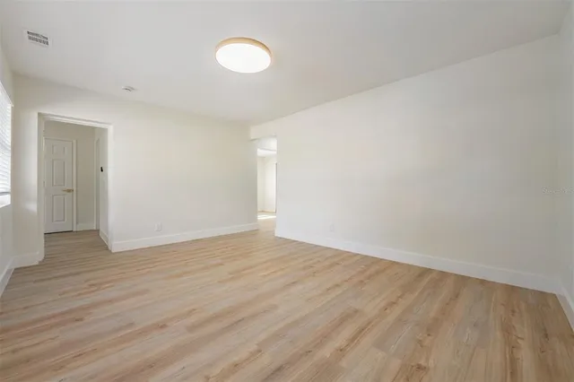 a view of an empty room with wooden floor and a window