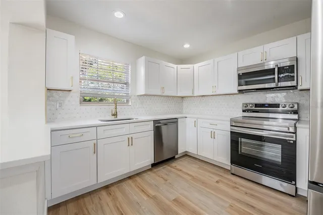 a kitchen with stainless steel appliances white cabinets a sink and a stove