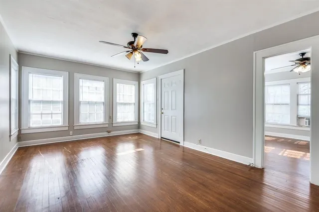 a view of empty room with wooden floor and fan