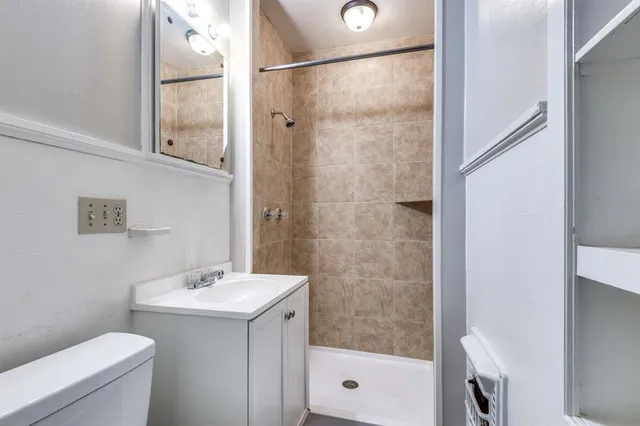 a bathroom with a shower sink vanity mirror and toilet