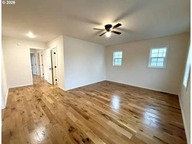 a view of empty room with wooden floor and fan